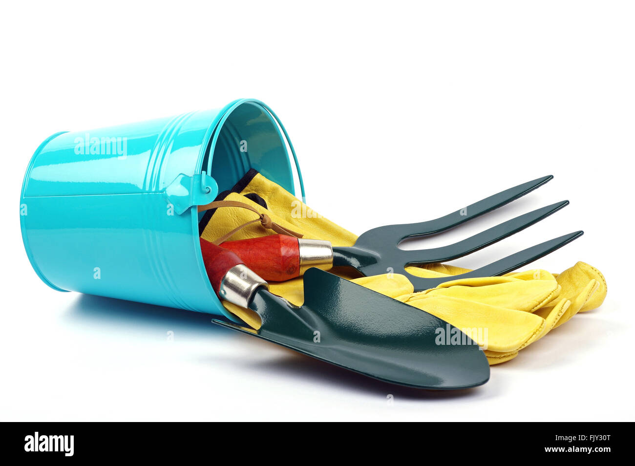 gardening tools including a green fork and green trowel with yellow gloves and a blue garden bucket on a clean white background Stock Photo