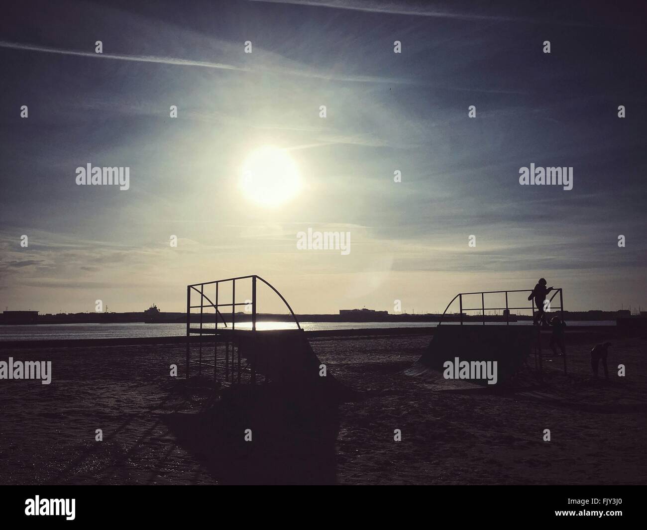 Children Playing On Sports Ramp At Beach Against Sky Stock Photo
