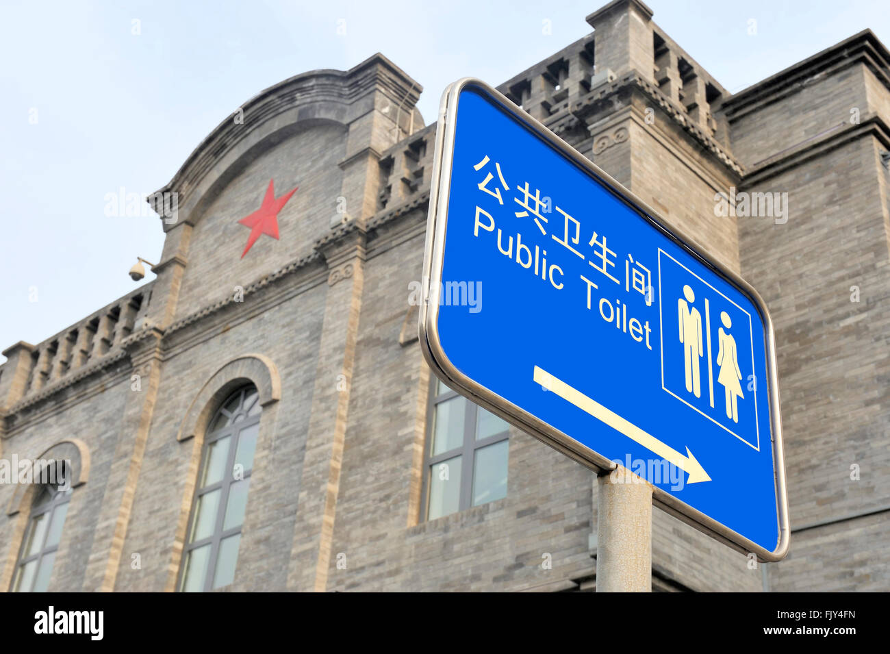 Sign in English and Chinese with text: Public Toilet.At background building with red cross Stock Photo