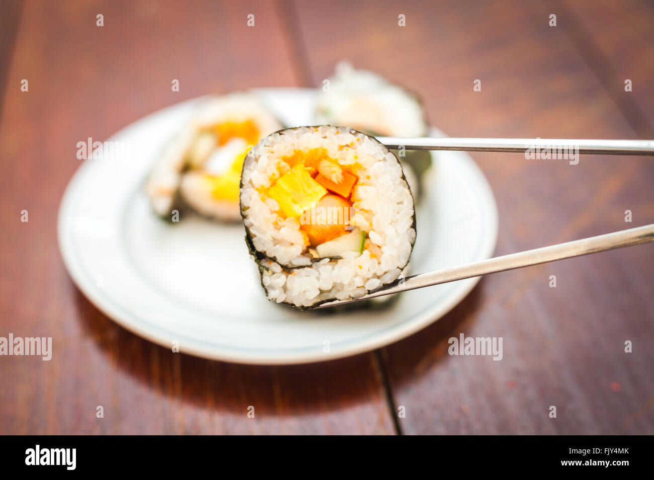 Rice sushi rolls assortment on white plate and gray chopsticks Stock Photo