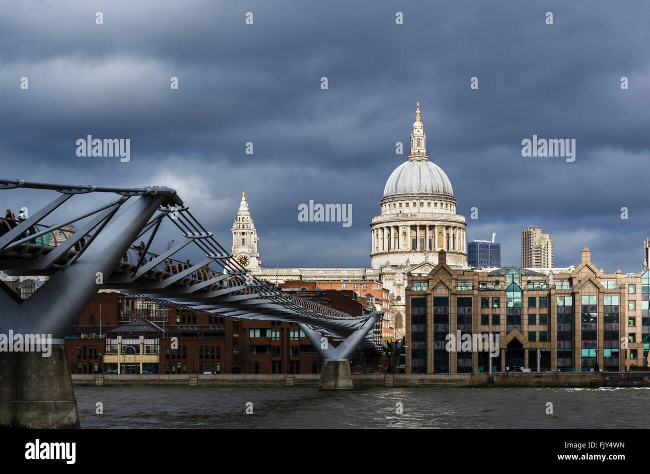Sun highlighting dome of St Paul's Cathedral before a storm, with River Thames and Millennium Bridge in foreground, London, UK Stock Photo