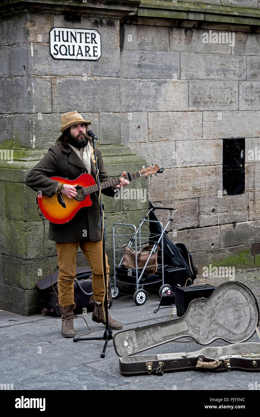 A busker playing guitar and singing in Hunter Square in Edinburgh's Old Town. Stock Photo