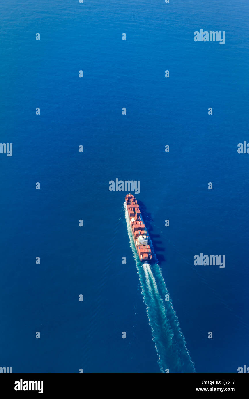 Aerial view of ship carrying freight to the port of New York in a bright blue ocean, vertical Stock Photo
