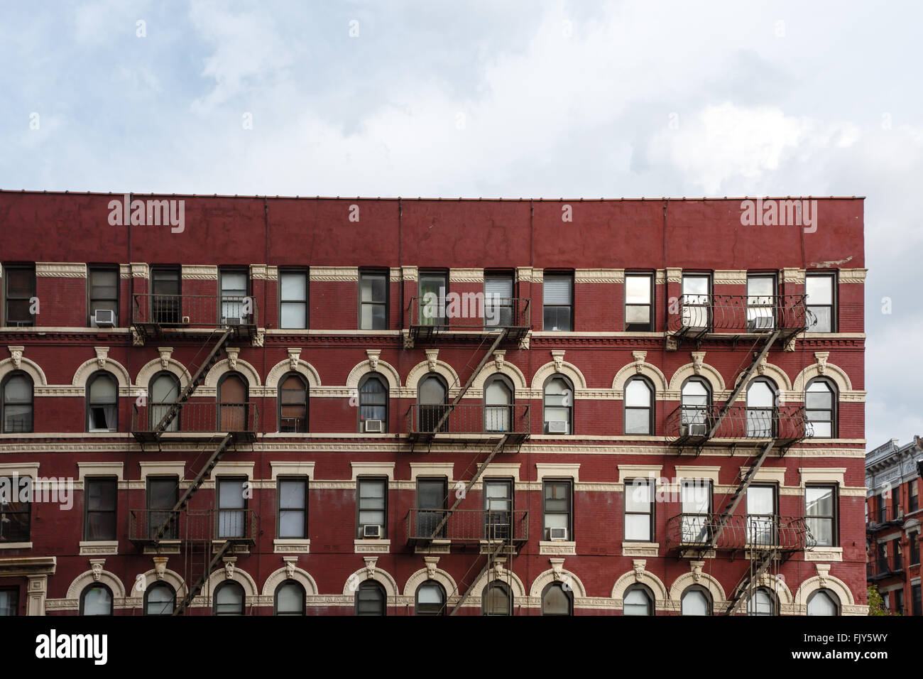 Pattern of fire escapes on side of older ornate brick building in New York City Stock Photo