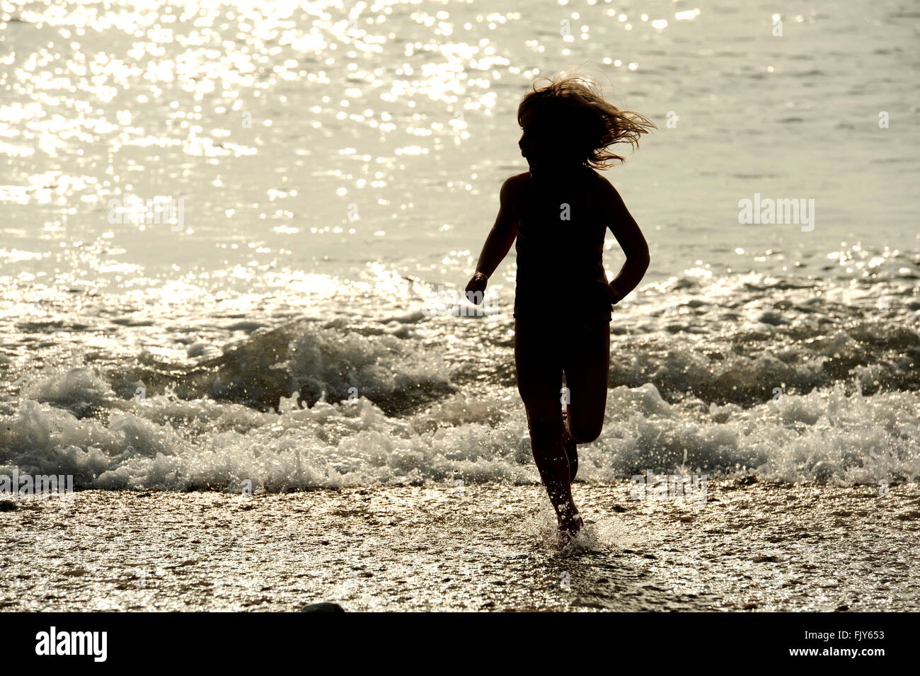 Child splashing in sparkling sea, Seaford, Easy Sussex, UK Stock Photo