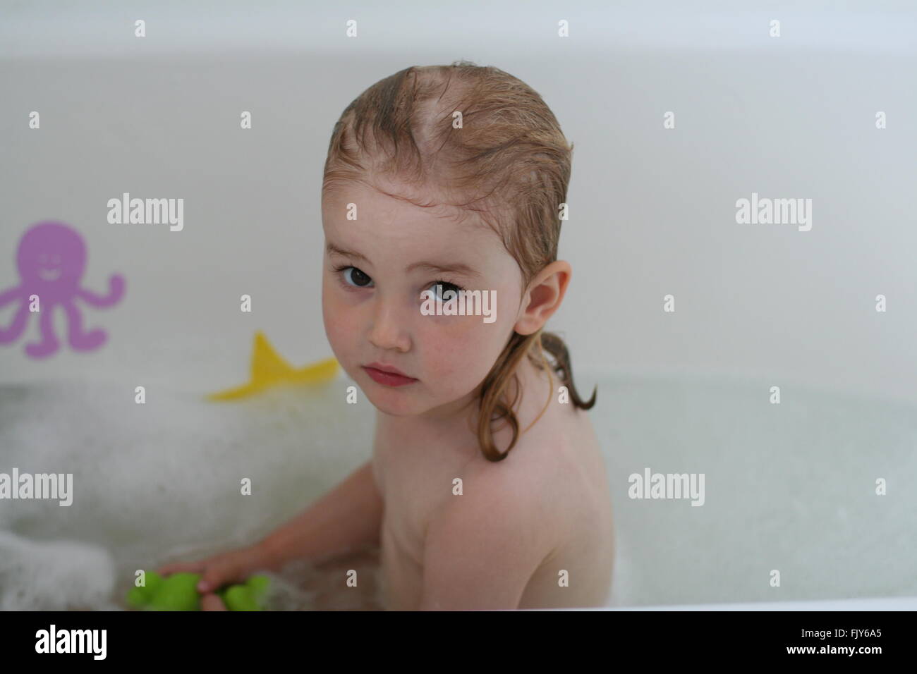 Little Girl Child Sitting In A White Bath With Wet Hair Staring