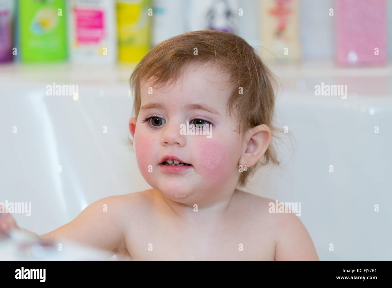 Happy cute little girl taking spa bath at home in water with foam and ...