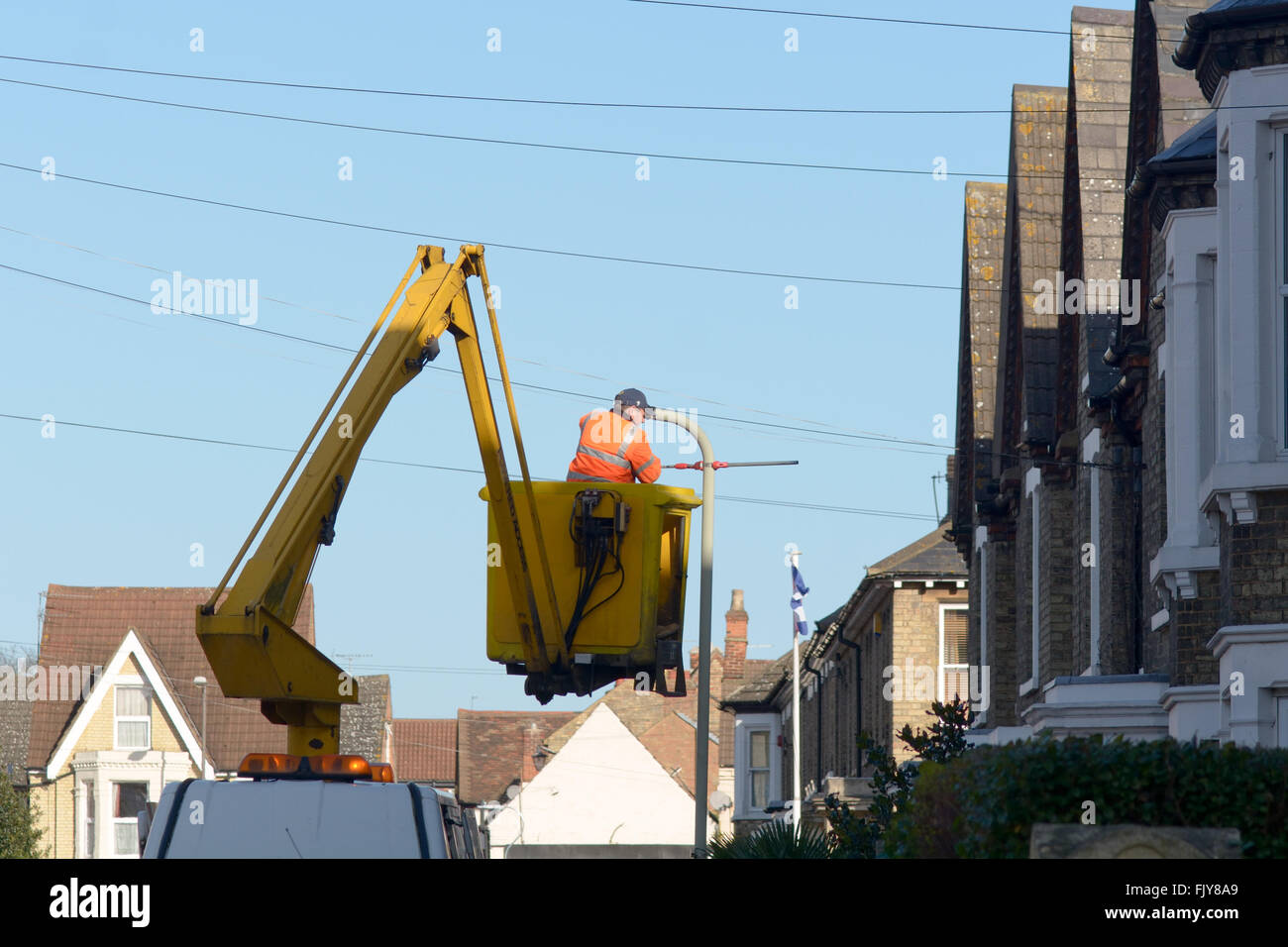 Workman replacing a lamp post light in a cherry picker boom lift in ...