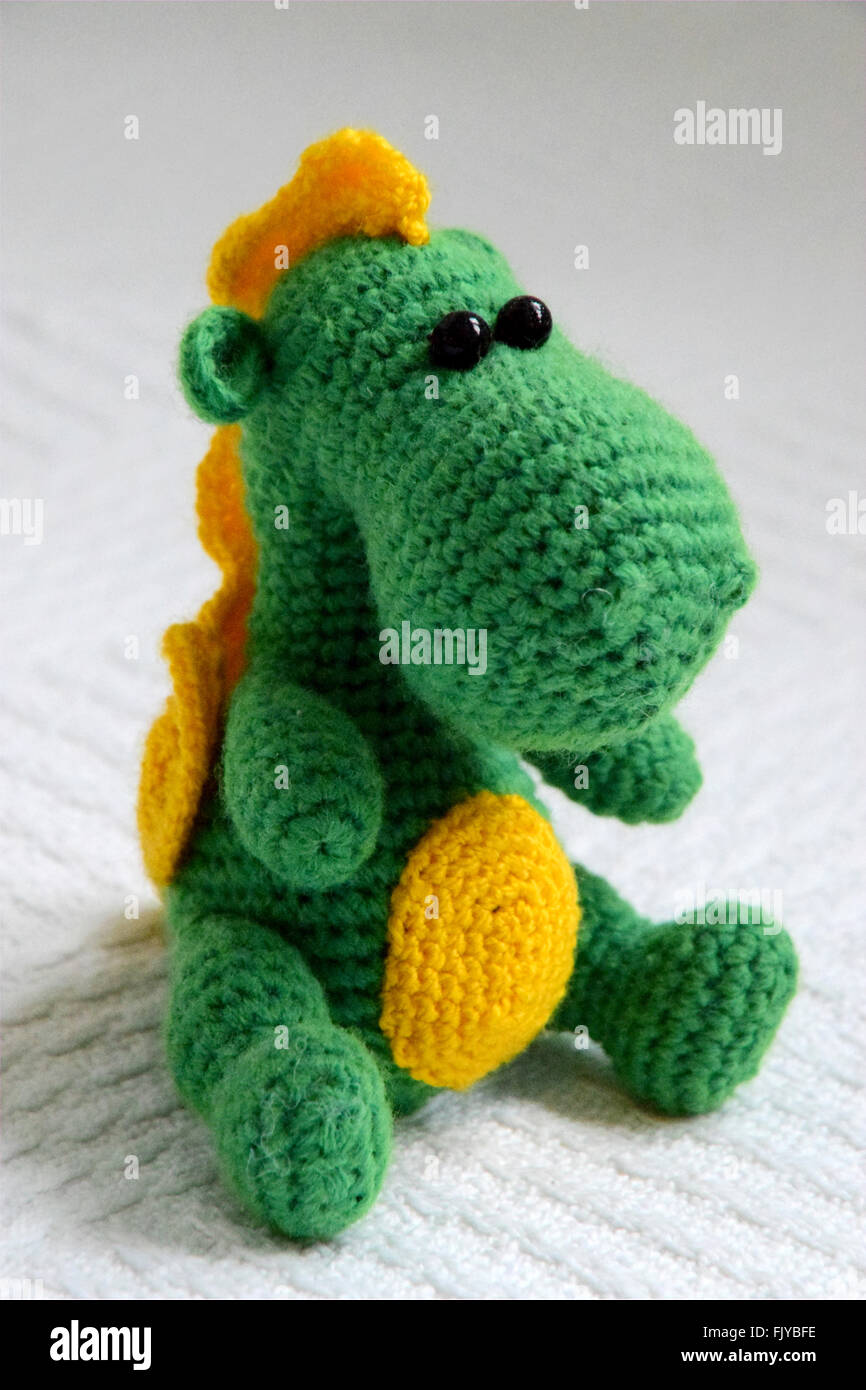 knitted toy green and yellow dragon on white background Stock Photo