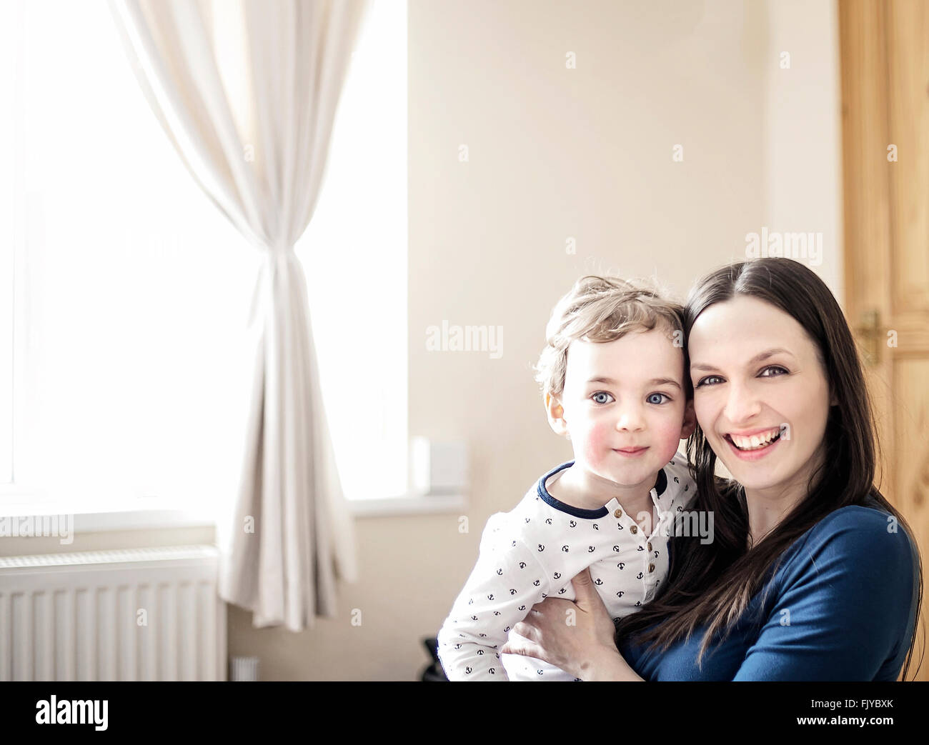 young mom with her small boy in arms at home Stock Photo