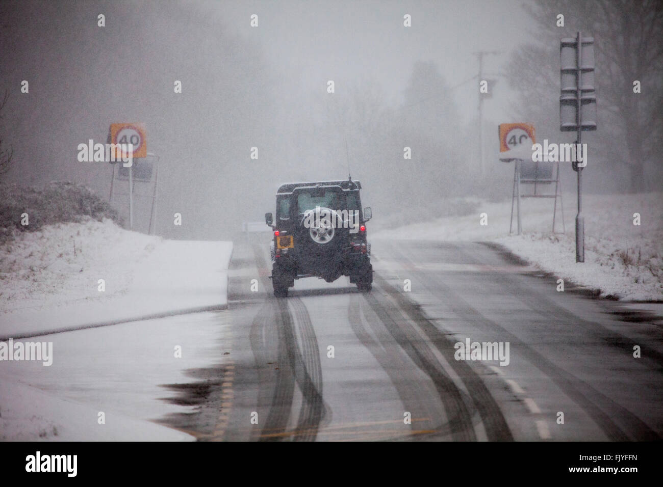 A 4x4 land rover tackling slipper snow wintry conditons on a rural road in blizzard conditions on Halkyn Mountain, Wales, UK Stock Photo