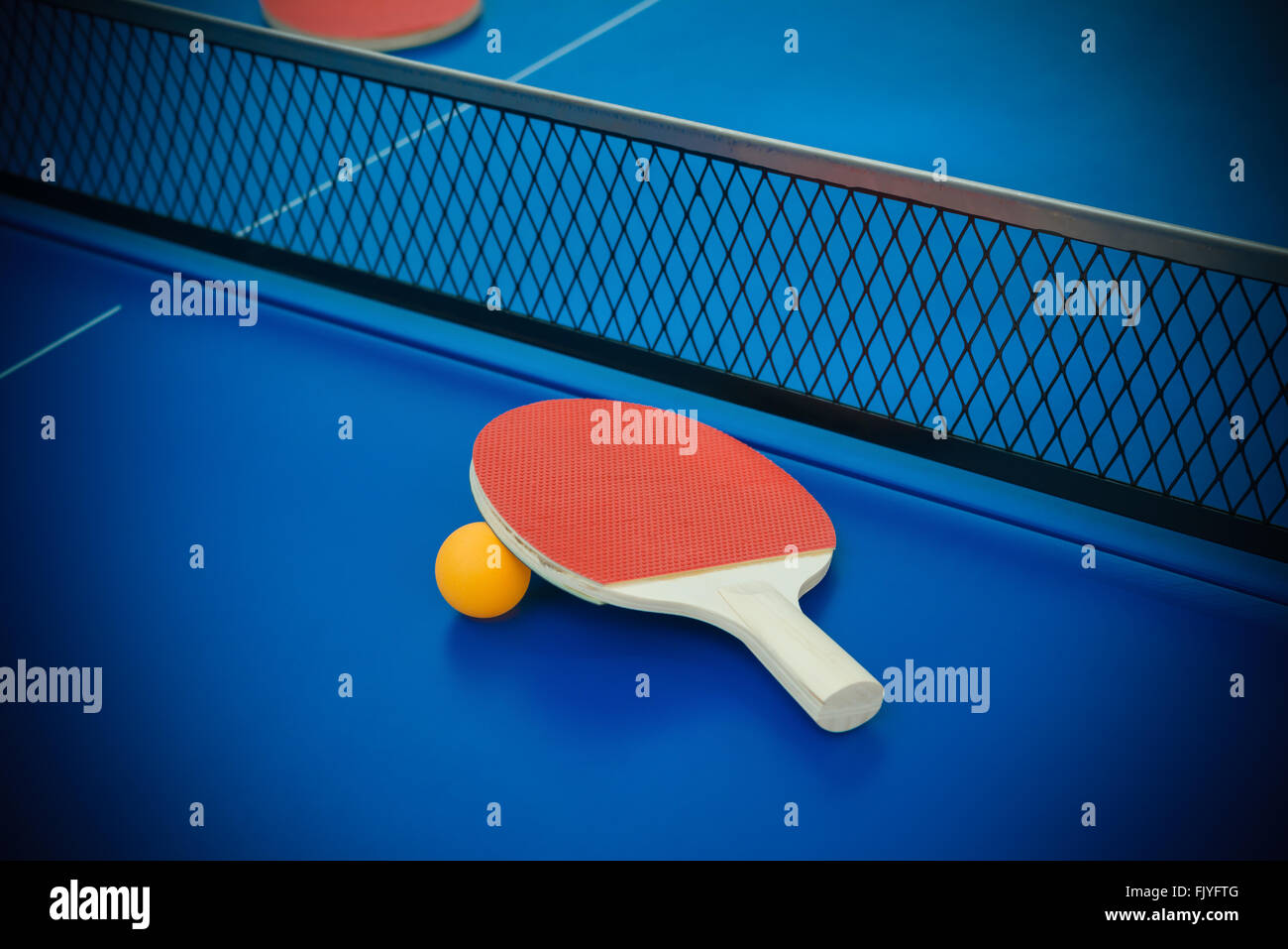 pingpong rackets and ball highlighted on a blue pingpong table Stock Photo