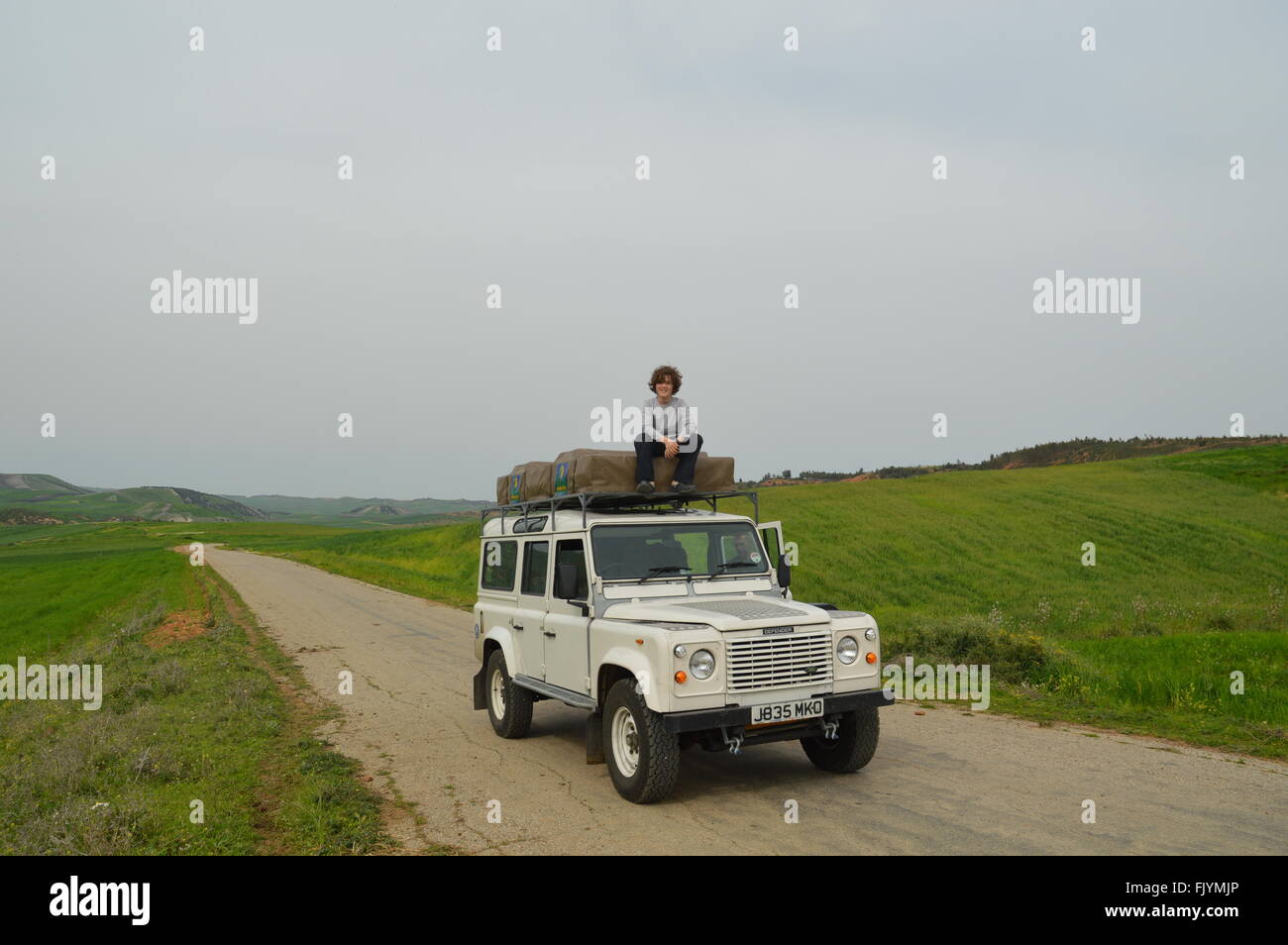 Boy sitting on top Land Rover Stock Photo