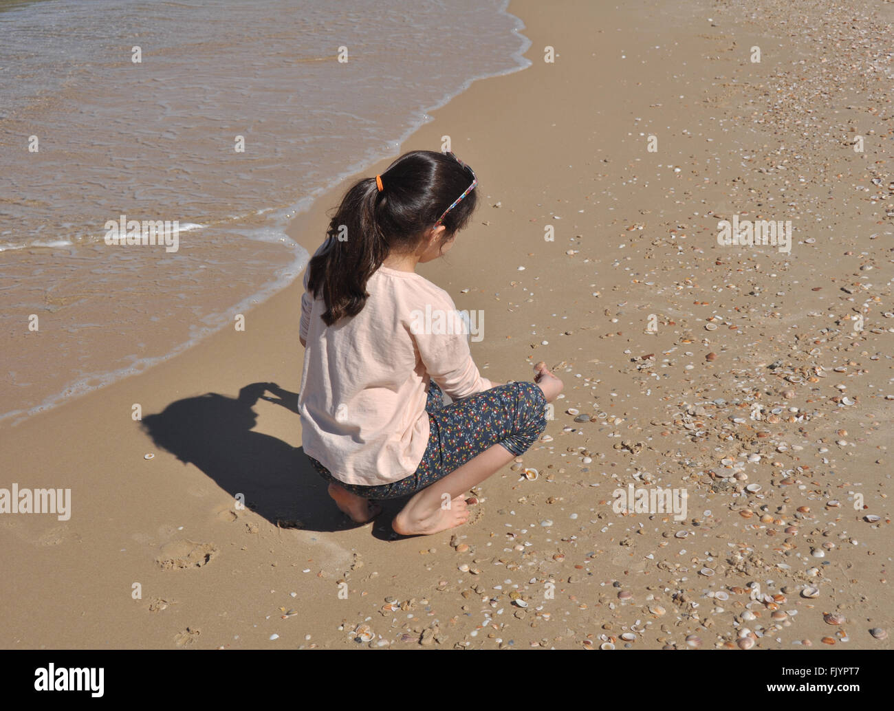 A girl picking up sea shells, Ashkelon beach, Israel. Stock Photo