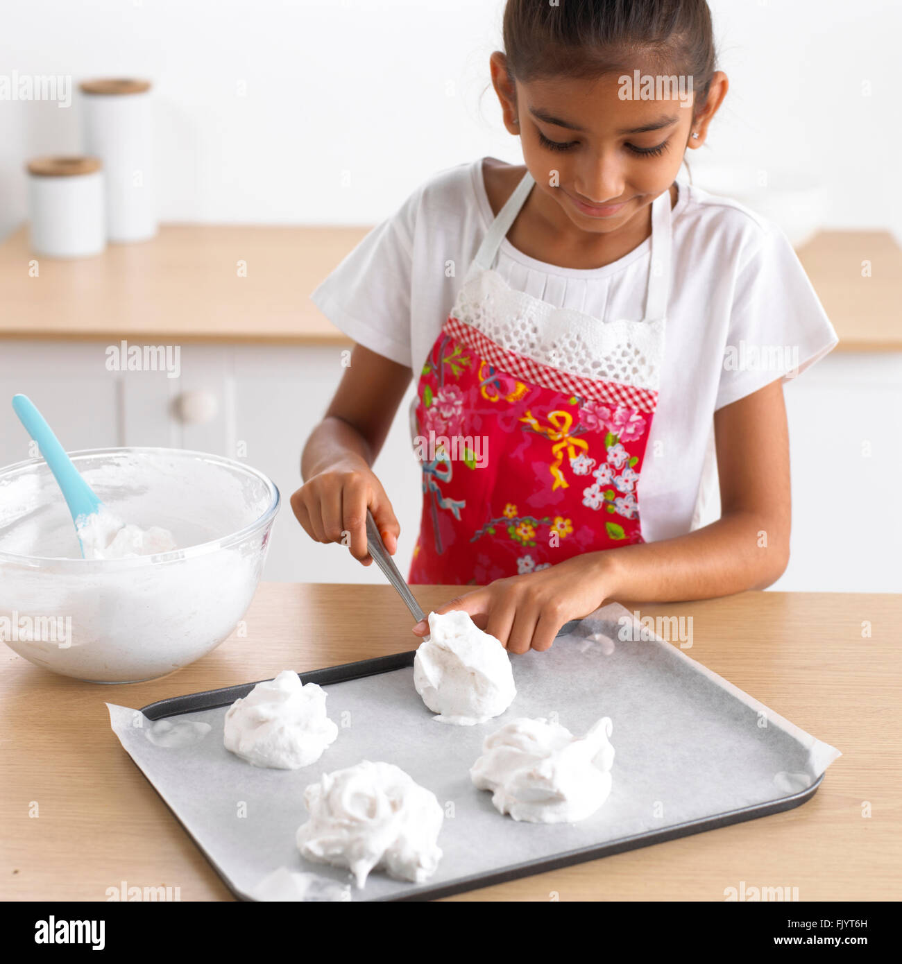 Spooning uncooked meringue onto baking tray, 8 years Stock Photo