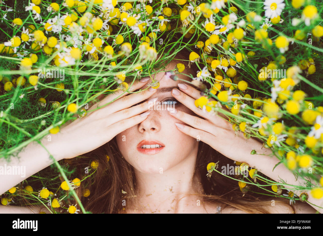 Portrait of young girl with blue eyes and freckles in chamomile field ...