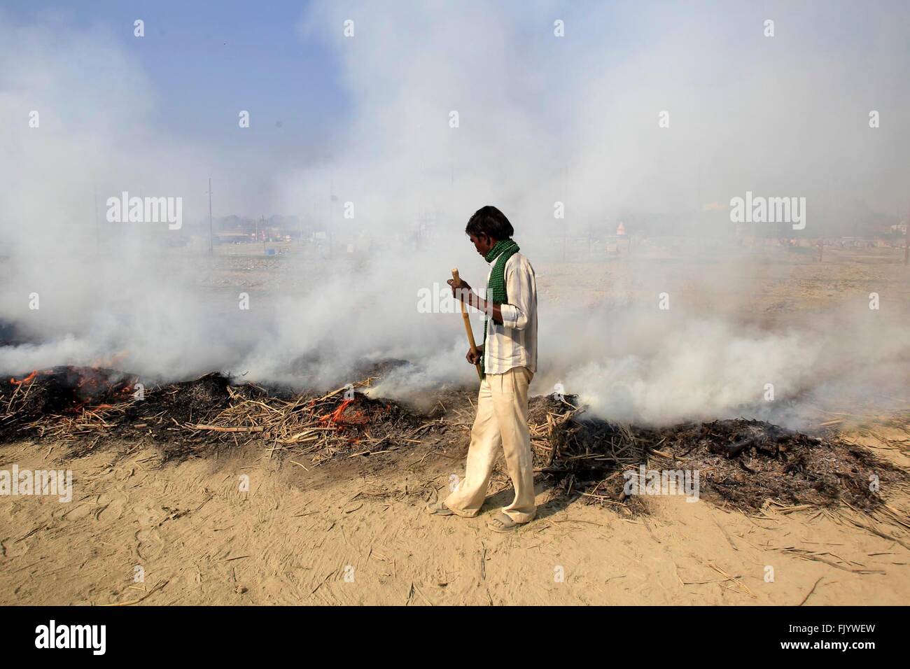 Allahabad, India. 03rd Mar, 2016. A man sweep near the smokes of burning garbage at the bank of the Ganga river after completion of the Magh Mela Festival in Allahabad. © Ravi Prakash/Pacific Press/Alamy Live News Stock Photo