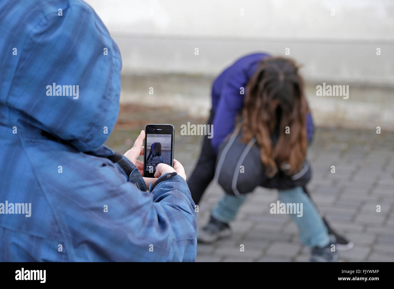 two kids fighting, third one making video with smartphone Stock Photo