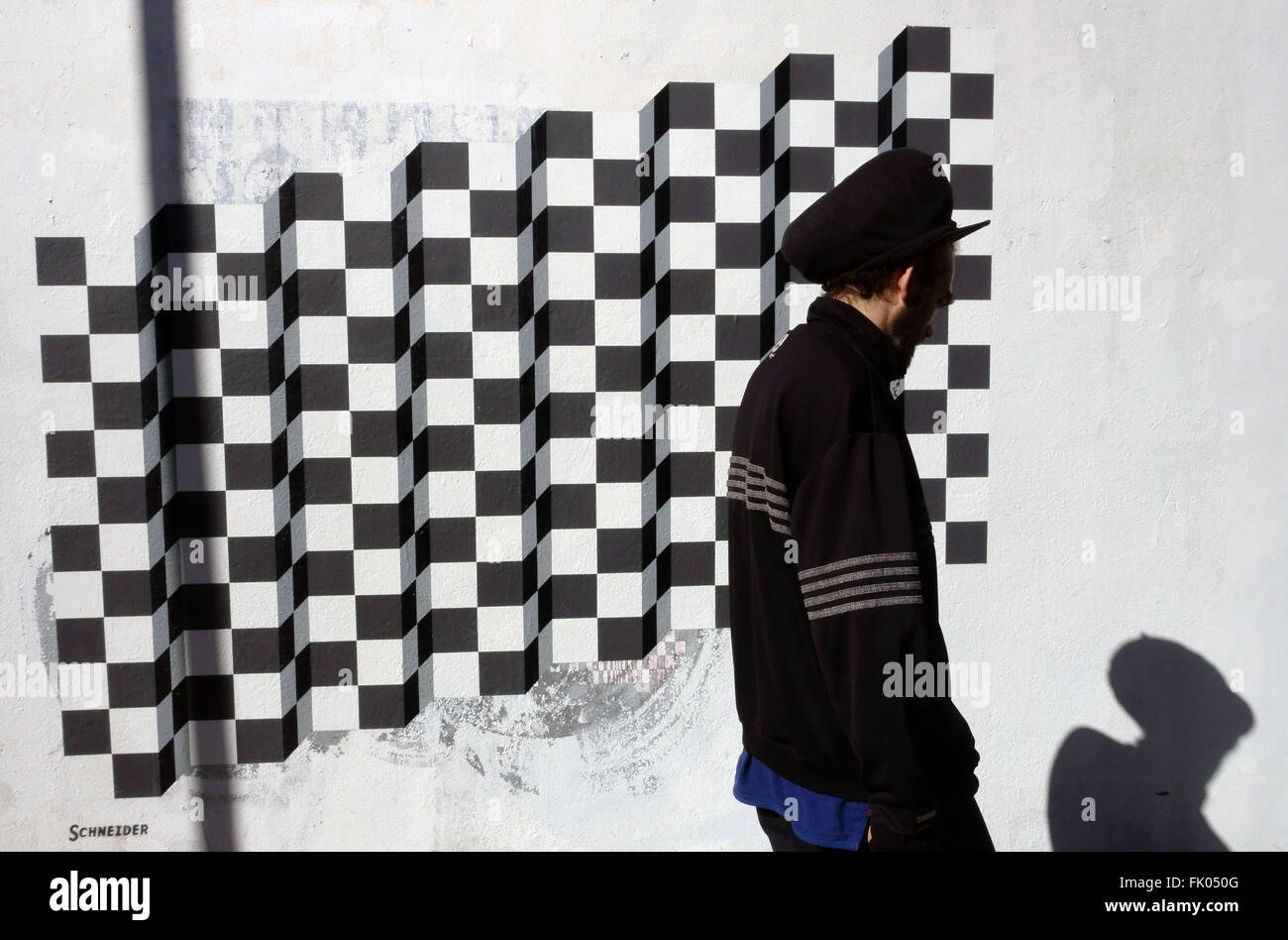 Man passes graffito by Schneider in Islington, London Stock Photo
