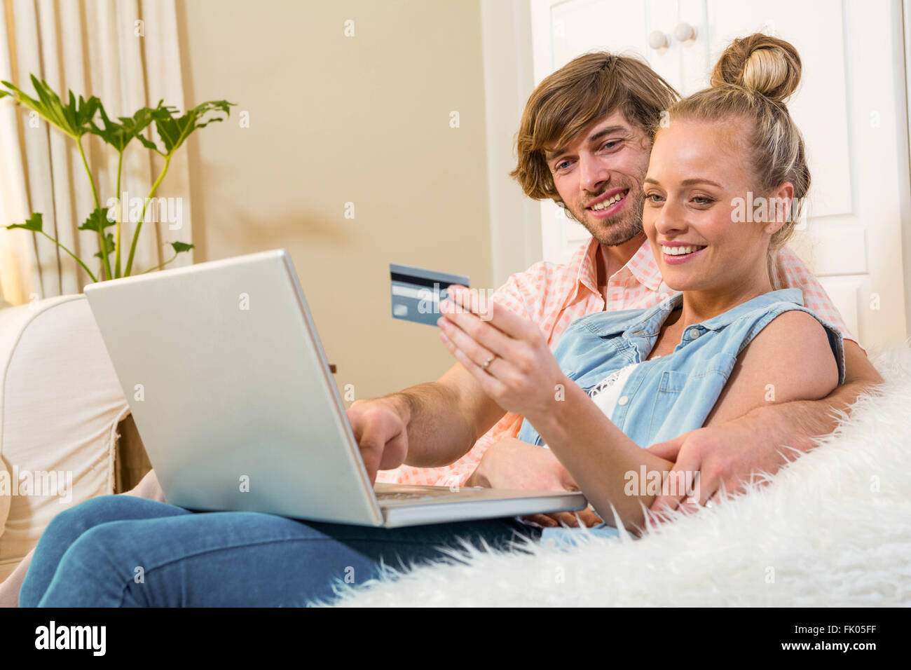 Cute couple using laptop to do online shopping sitting on the couch ...