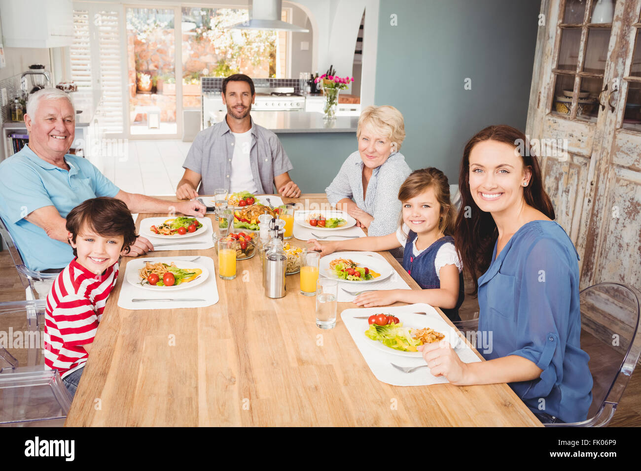 Smiling family with grandparents sitting at dining table Stock Photo ...