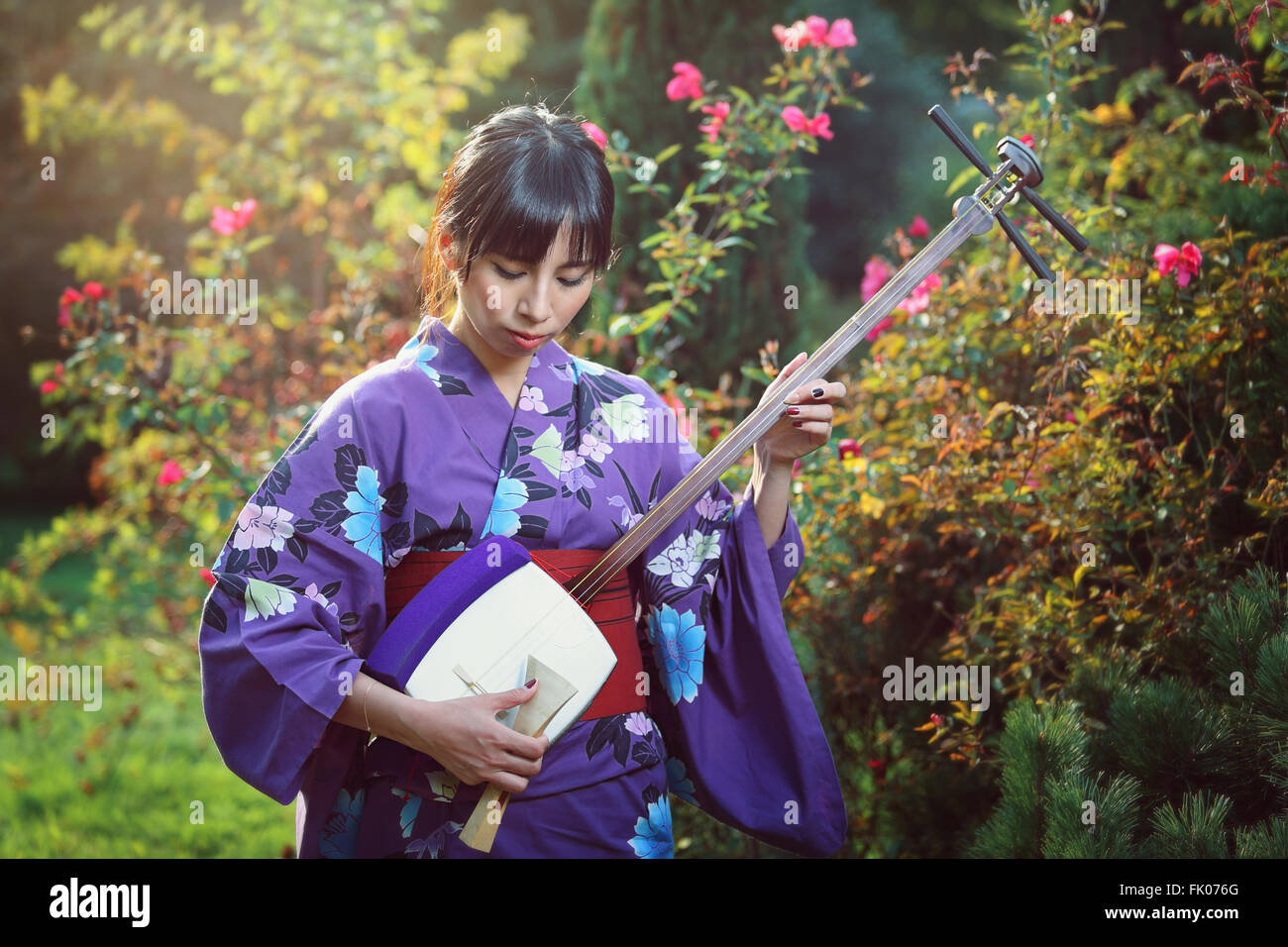 Beautiful japanese woman playing traditional music instrument. Outdoor portrait Stock Photo