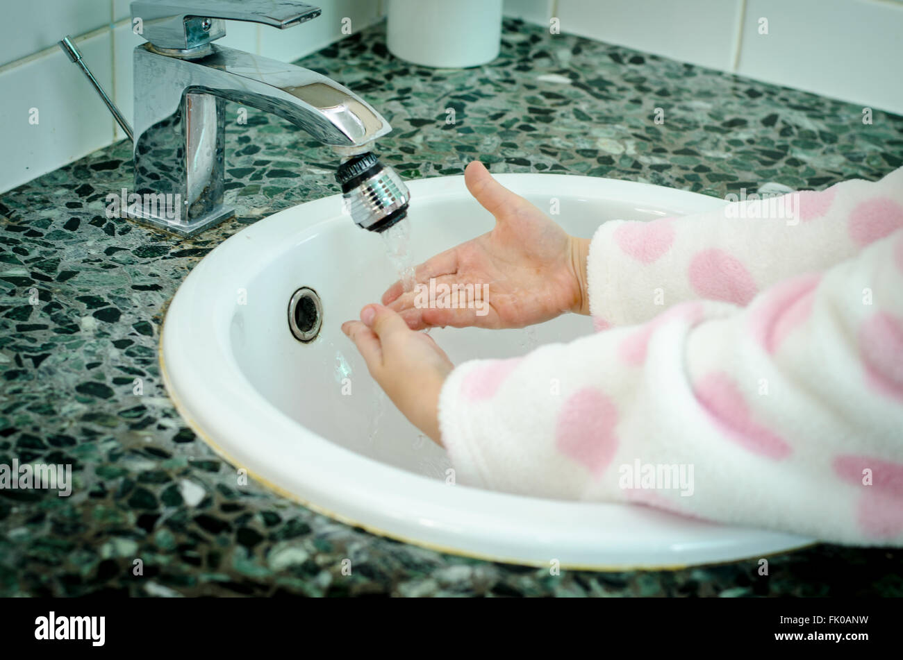 child washing hands under pouring water in the bathroom Stock Photo
