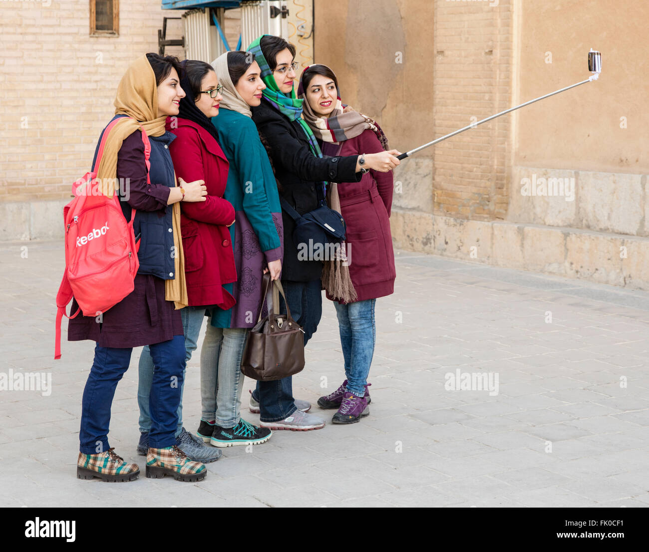 Five fashionably clad women pose for a selfie in courtyard of Armenian cathedral, Isfahan, Iran Stock Photo