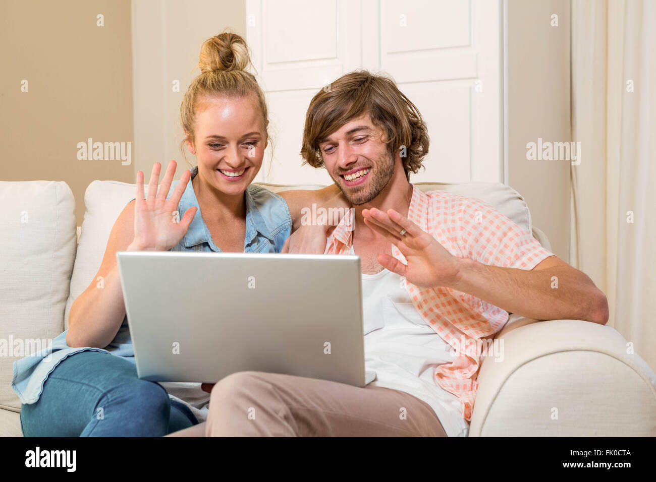 Cute couple using laptop sitting on the couch Stock Photo - Alamy