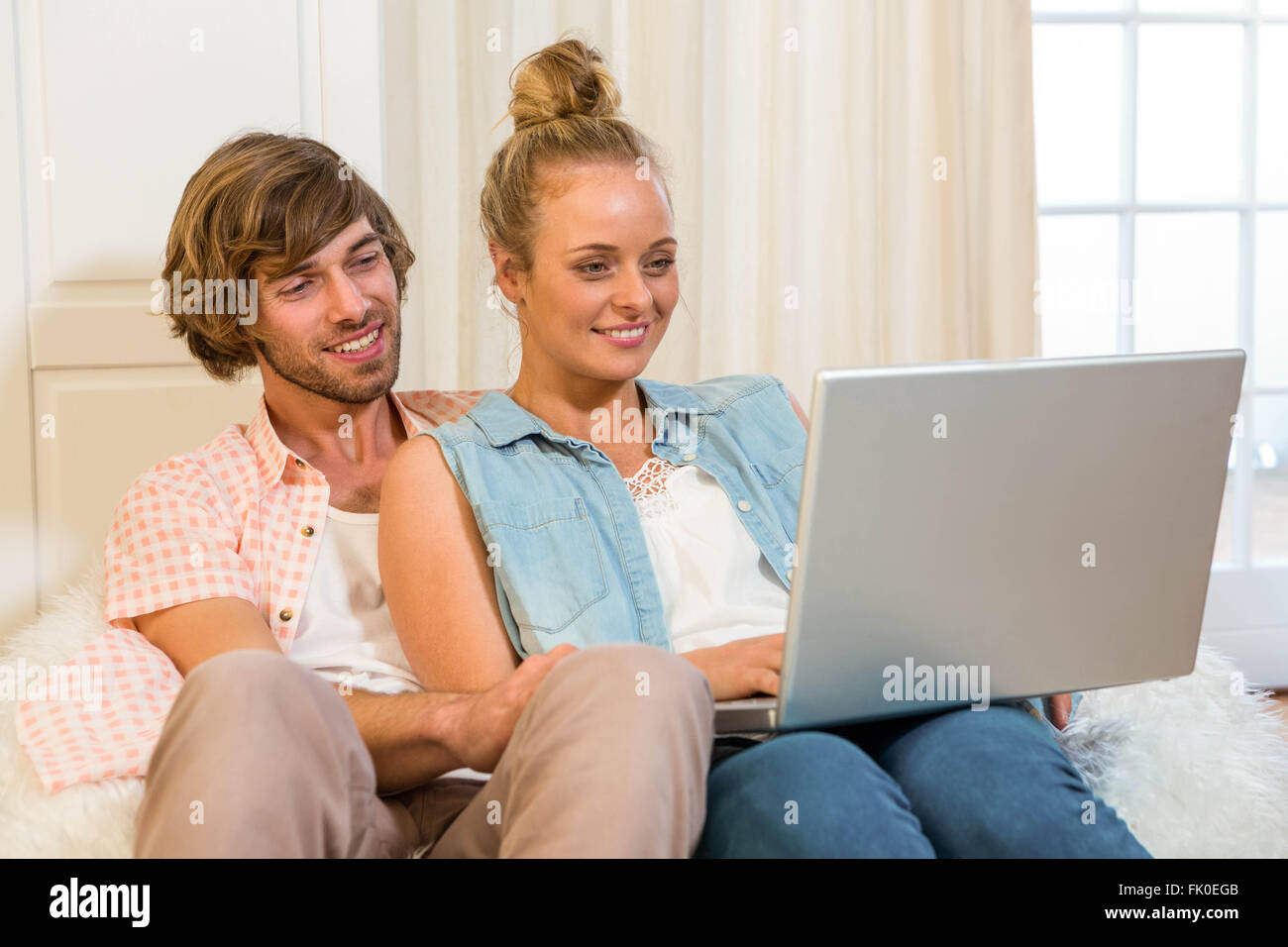 Cute couple using laptop sitting on the couch Stock Photo - Alamy