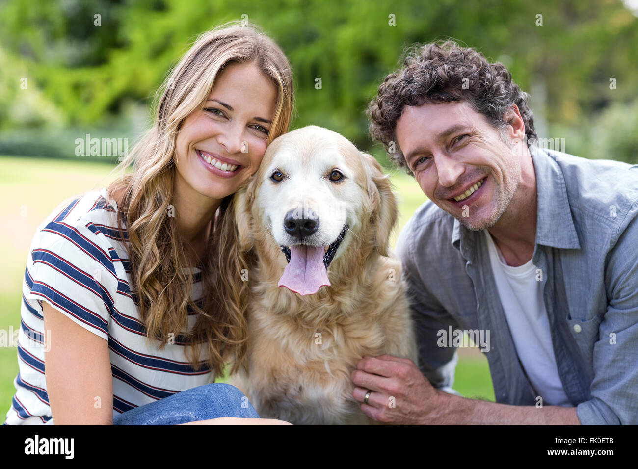 Smiling couple with dog in the park Stock Photo - Alamy