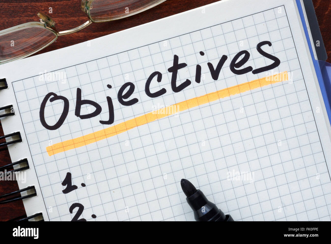 Objectives concept  written in a notebook on a wooden table. Stock Photo