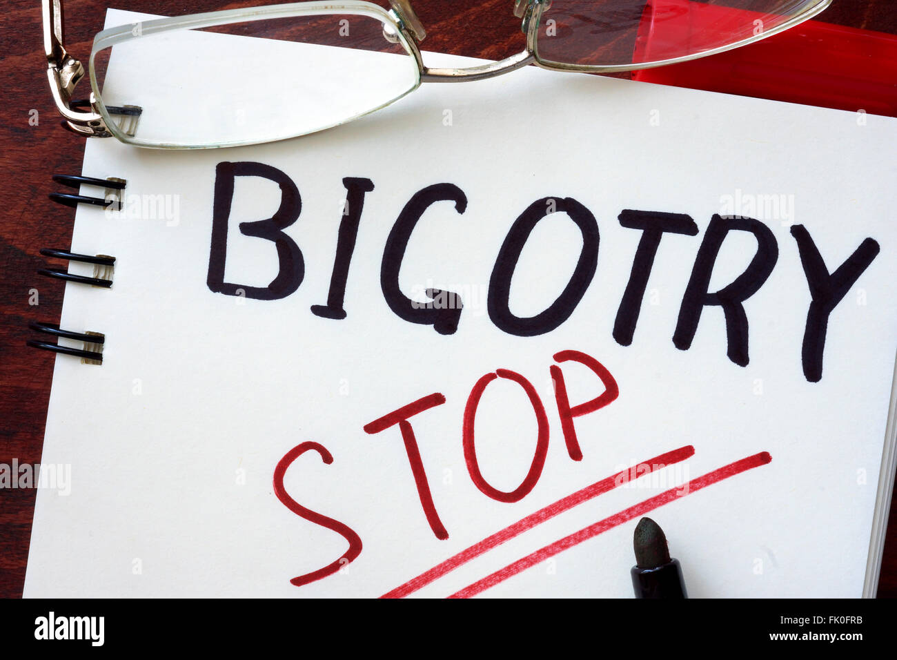 Stop Bigotry concept  written in a notebook on a wooden table. Stock Photo