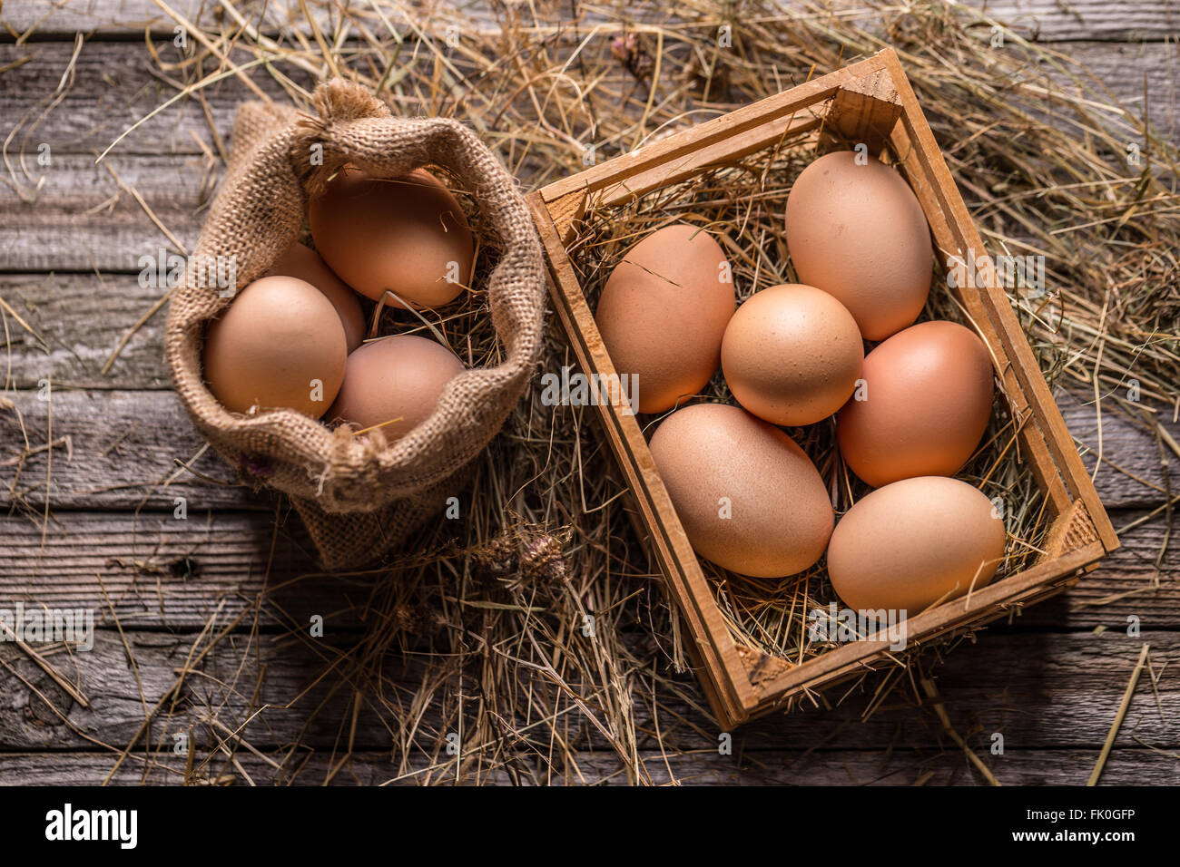 Bunch of fresh brown eggs in a wooden crate and in burlap sack Stock Photo