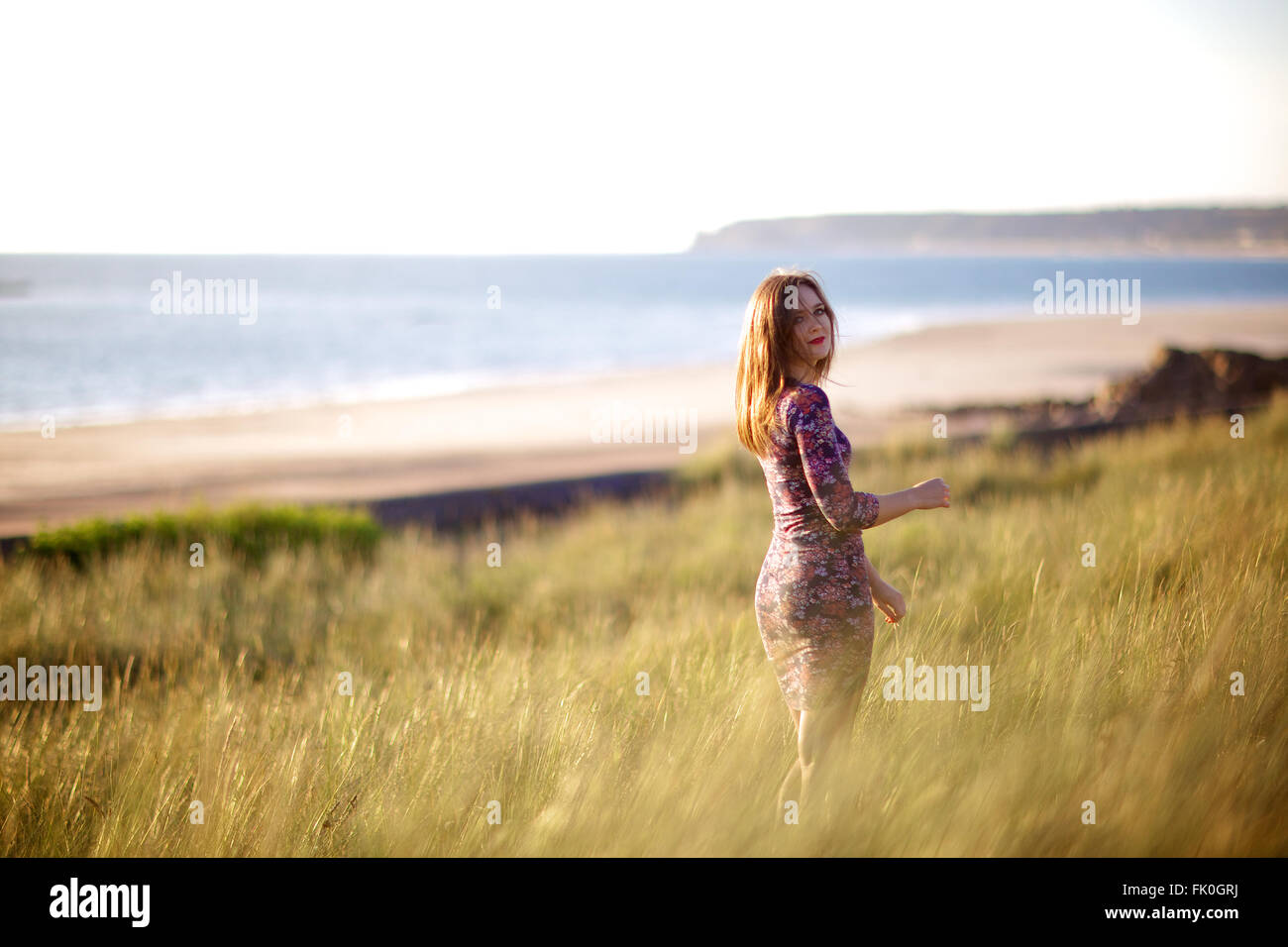Young women in floral dress among nature, long natural green grass and Bunny Tails (Lagurus ovatus) Stock Photo
