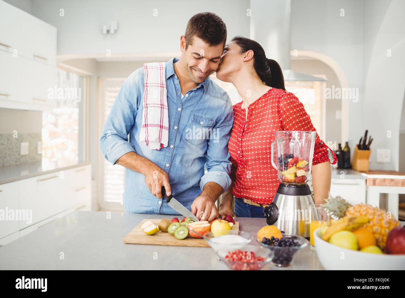 Woman kissing man preparing fruit juice Stock Photo