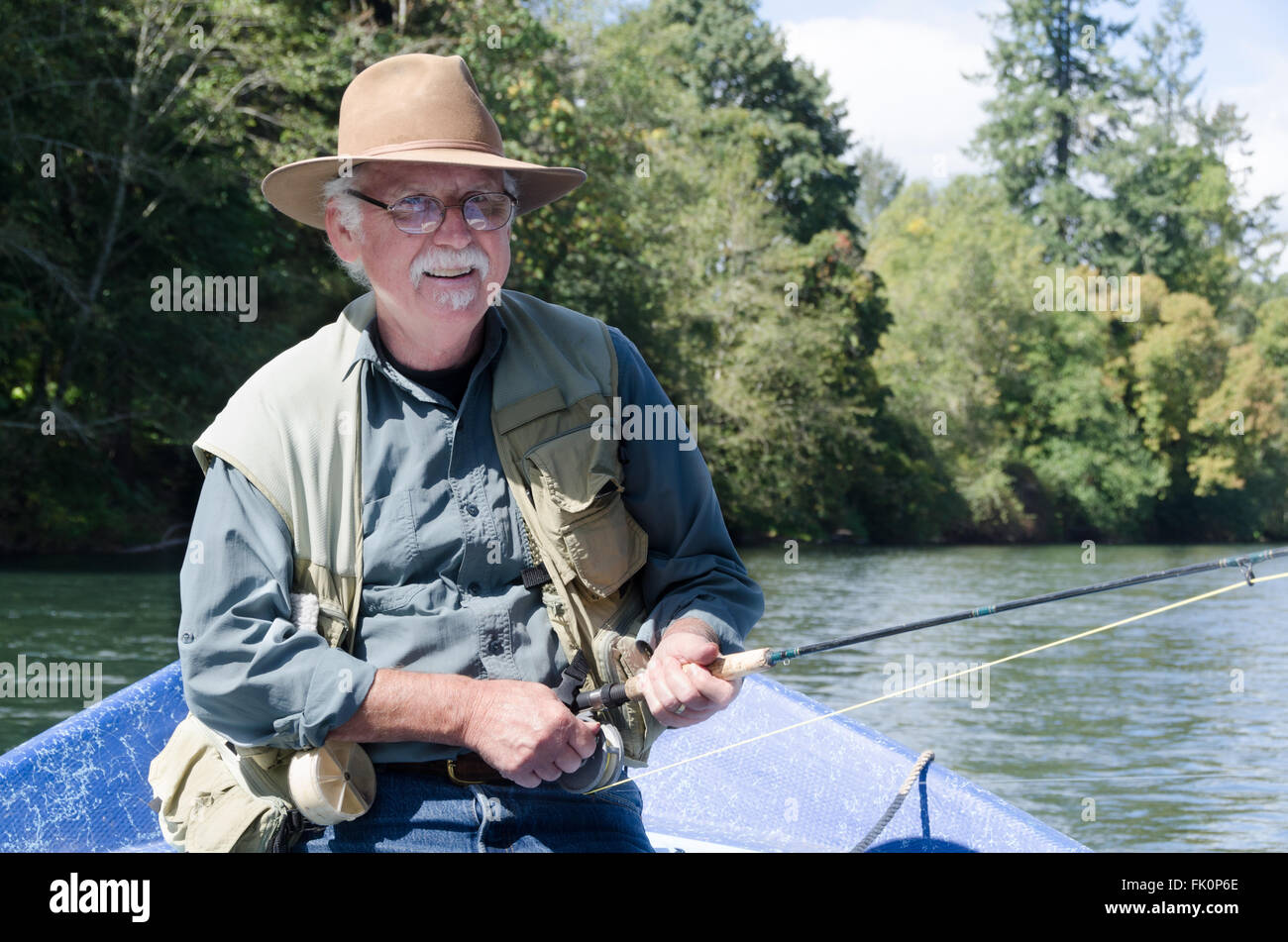 Portrait of a happy retired senior man spending time on the water fishing. Stock Photo