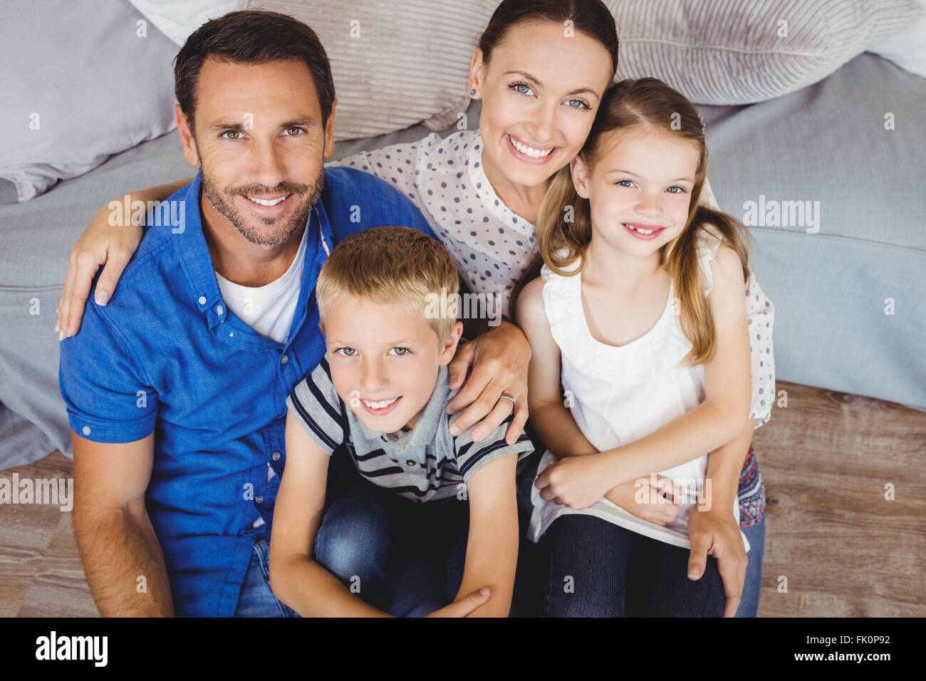 Portrait of cheerful family sitting by sofa Stock Photo