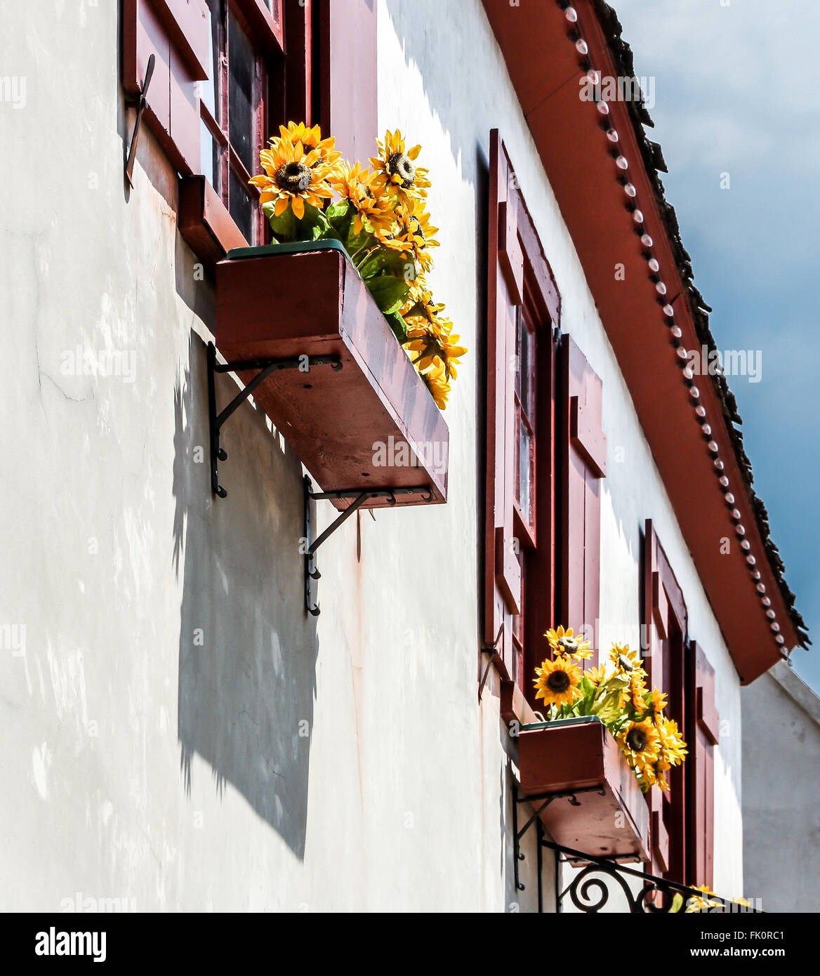 Flowerboxes in three windows with yellow flowers Stock Photo