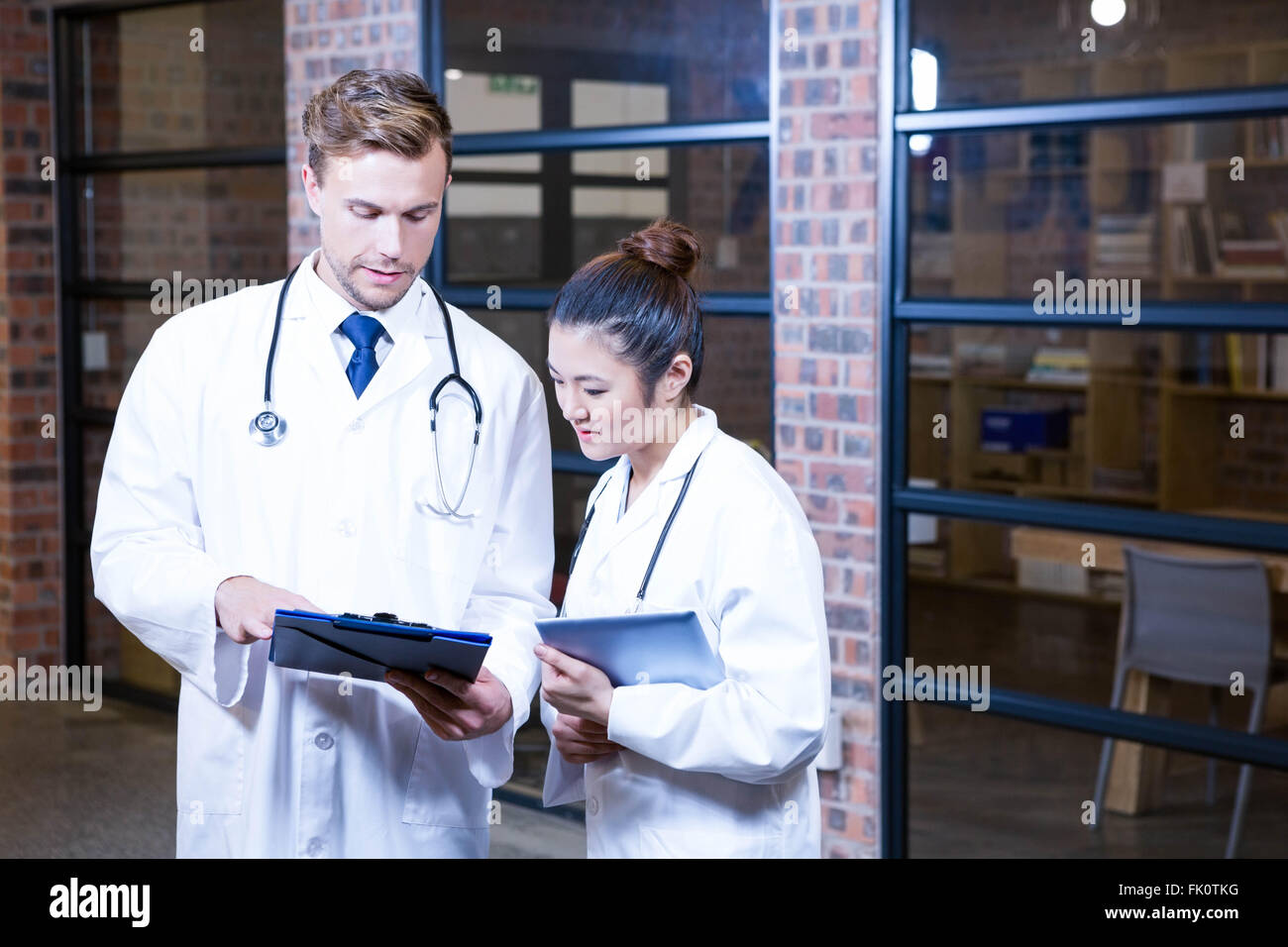 Two doctors looking at clipboard and discussing near library Stock ...