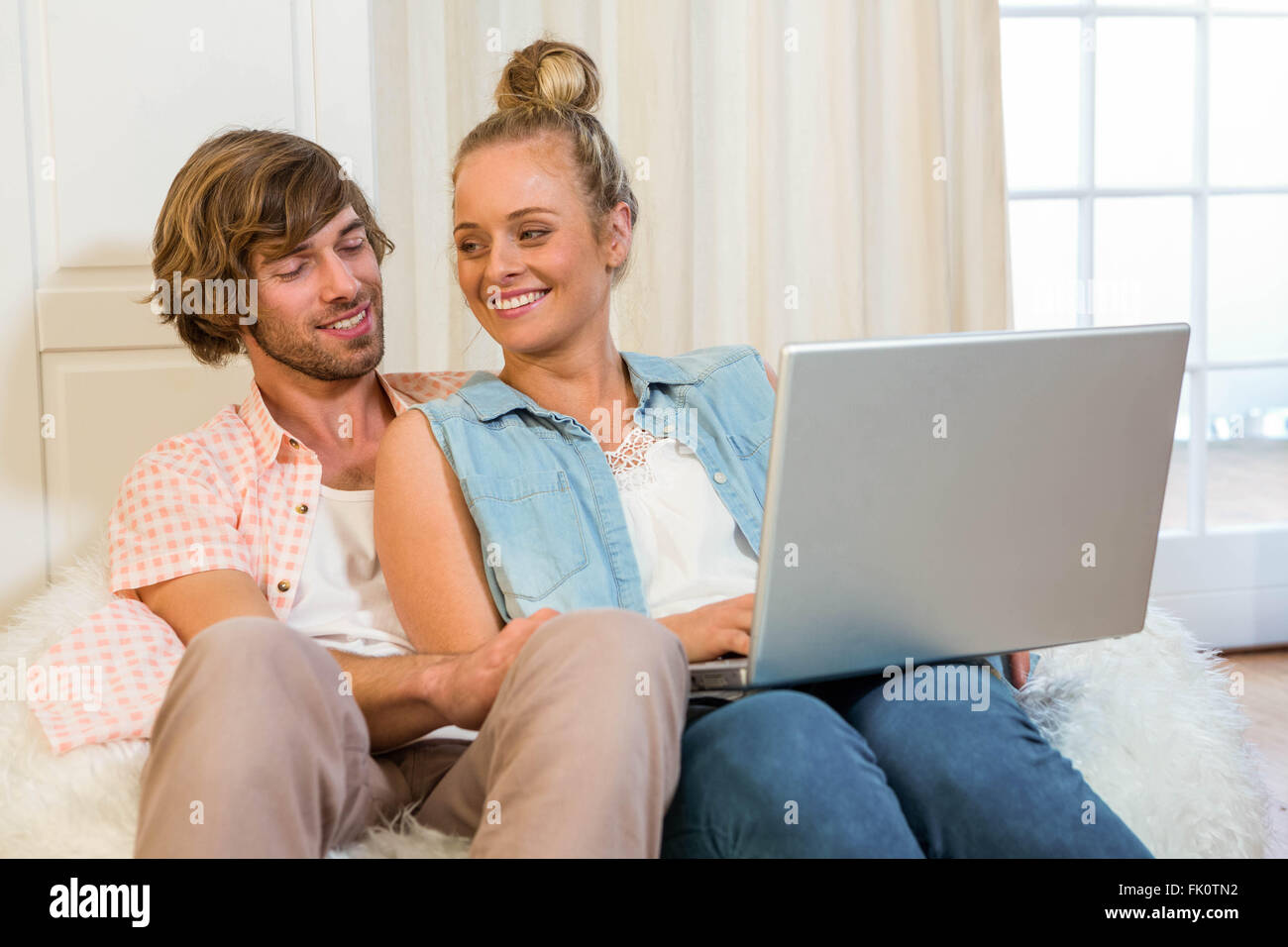 Cute couple using laptop sitting on the couch Stock Photo - Alamy
