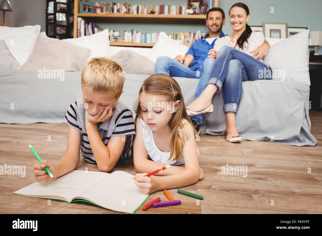 Children coloring on book while parents looking at them Stock Photo