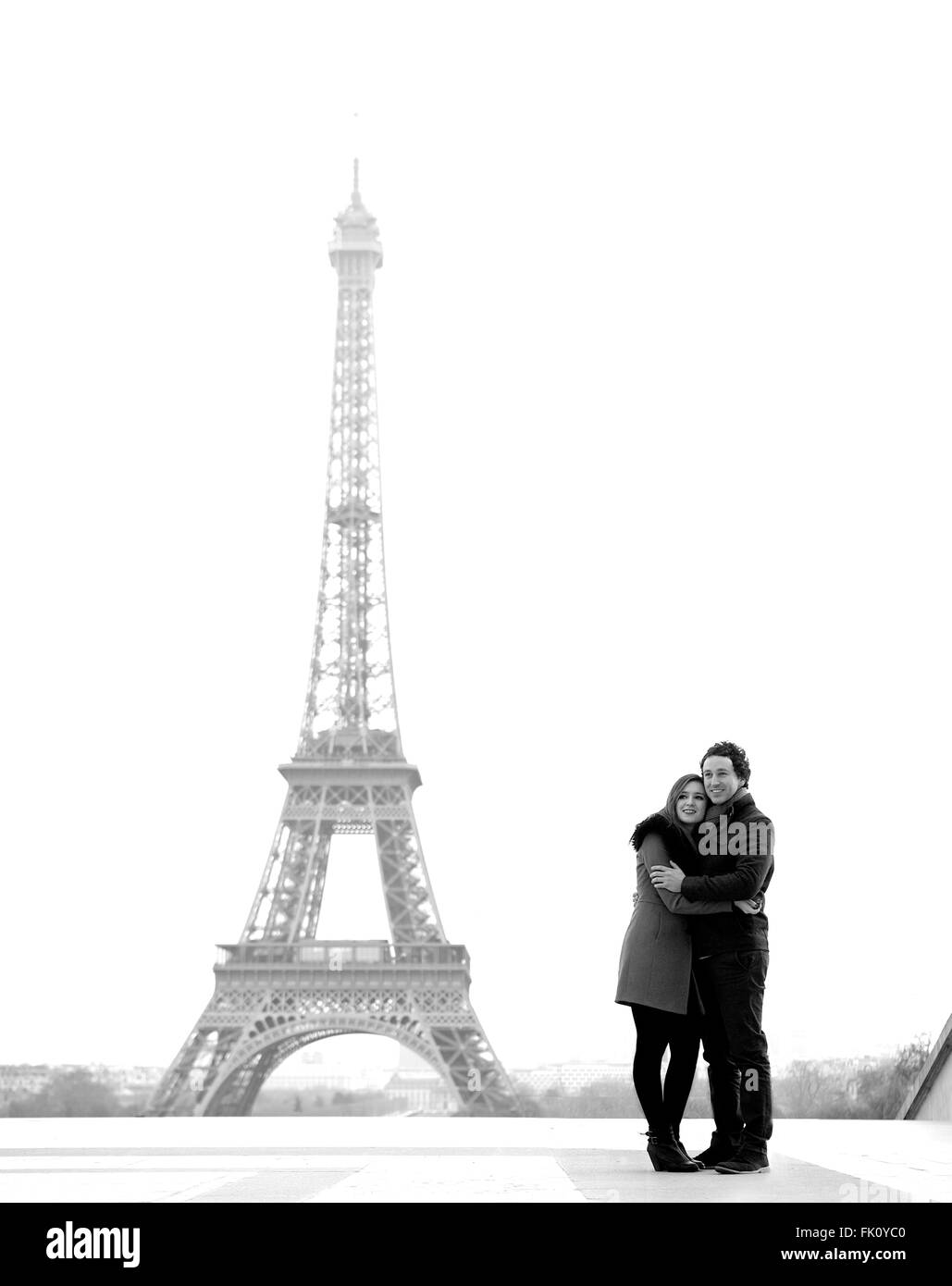 Young and in love brunette couple in front of Eiffel tower, Paris, at Trocadero overlooking the city during the day - Stock Photo