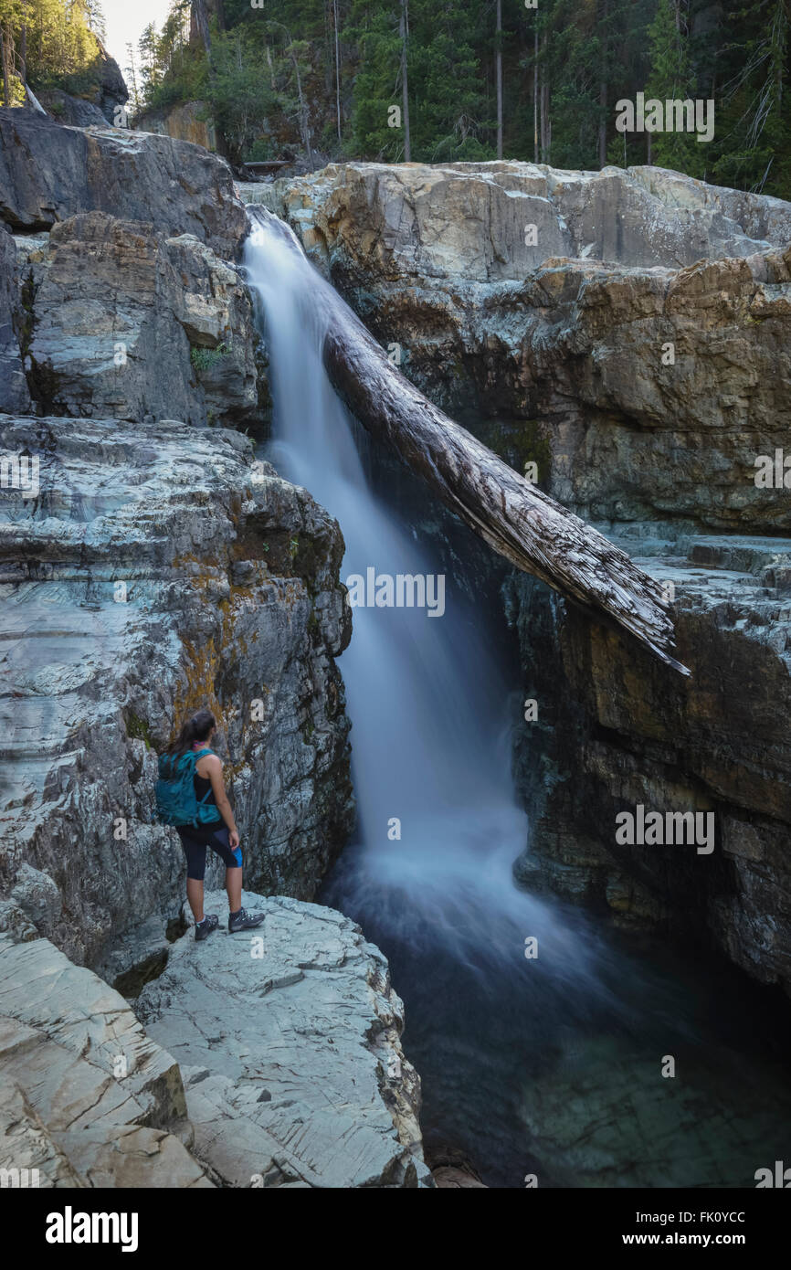 Female Hiker admiring Myra Falls in Strathcona Provincial Park near Campbell River, BC Stock Photo