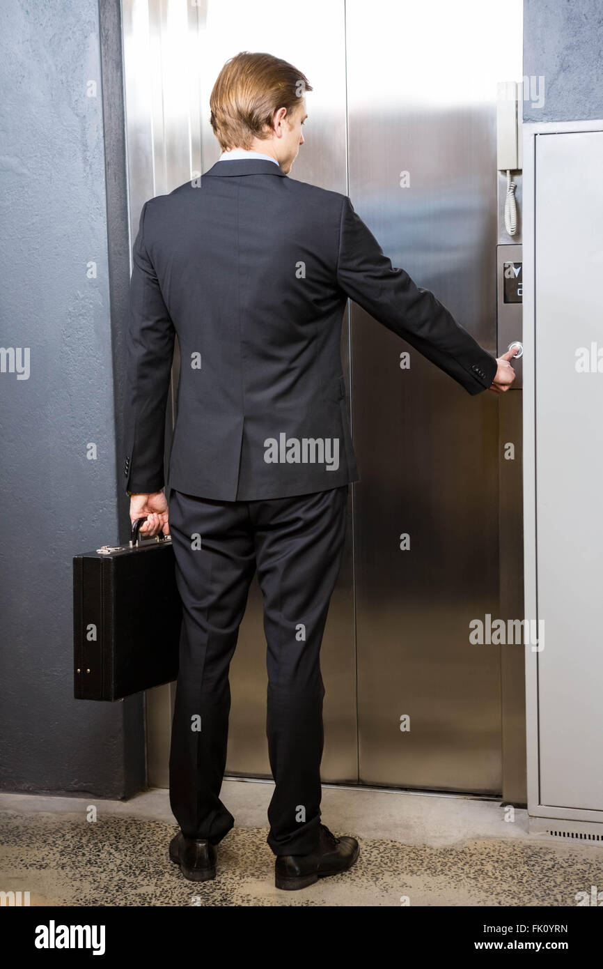 Businessman pressing elevator button Stock Photo Alamy