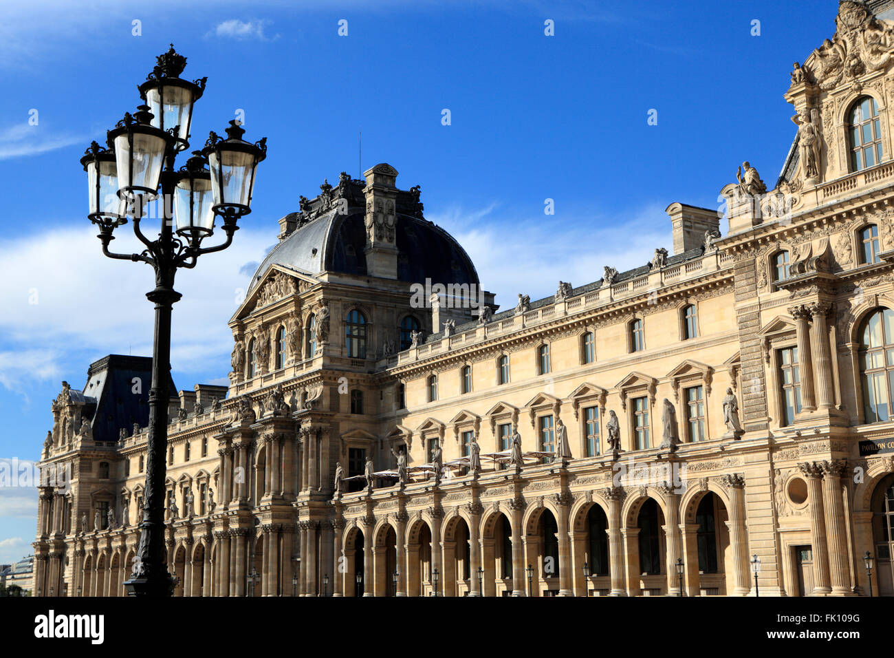 Renaissance architecture and street lamps at the Louvre Museum in Paris bathed in warm late afternoon light. Stock Photo