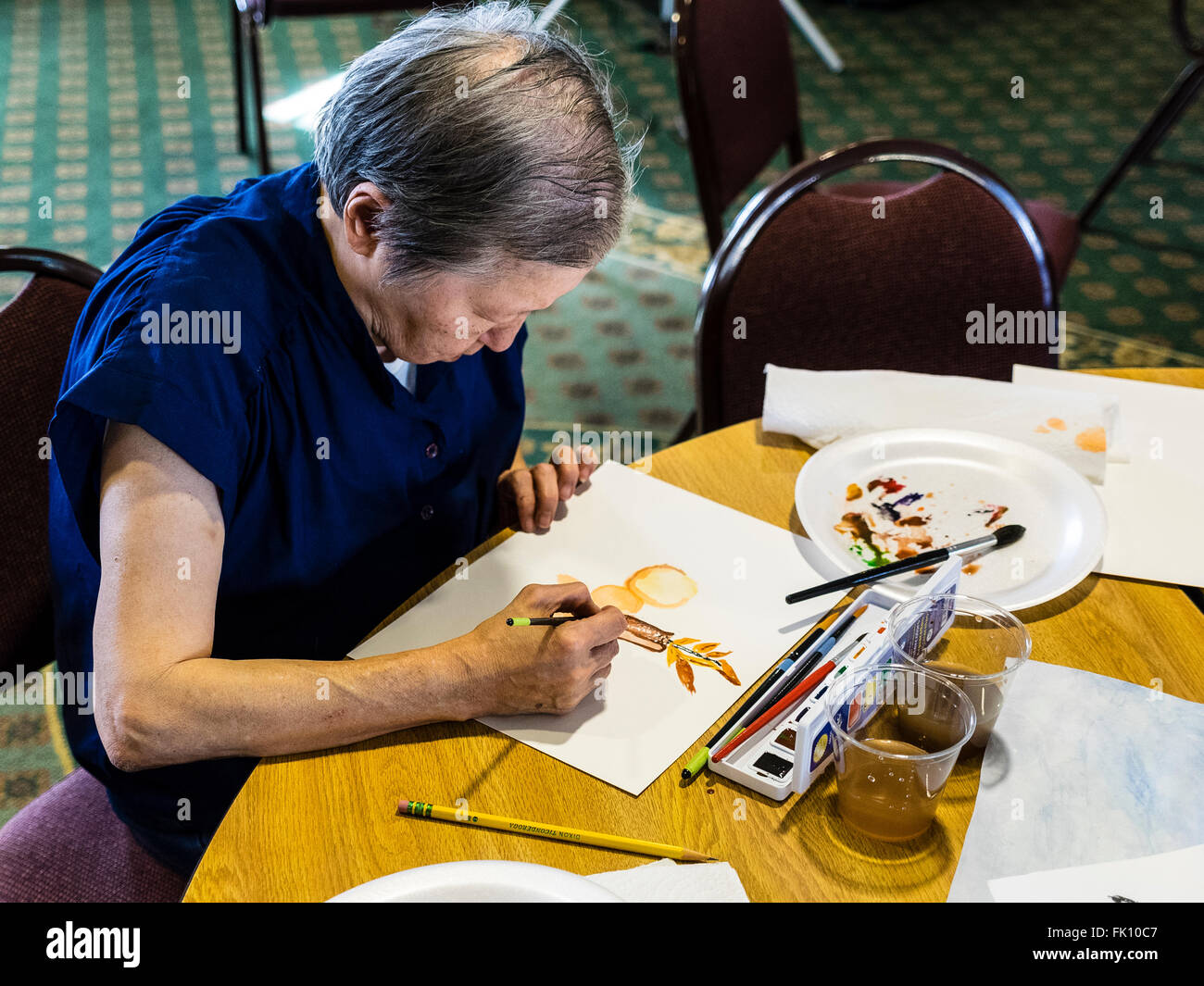 A Female Senior Citizen Paints In A Watercolor Class For Seniors