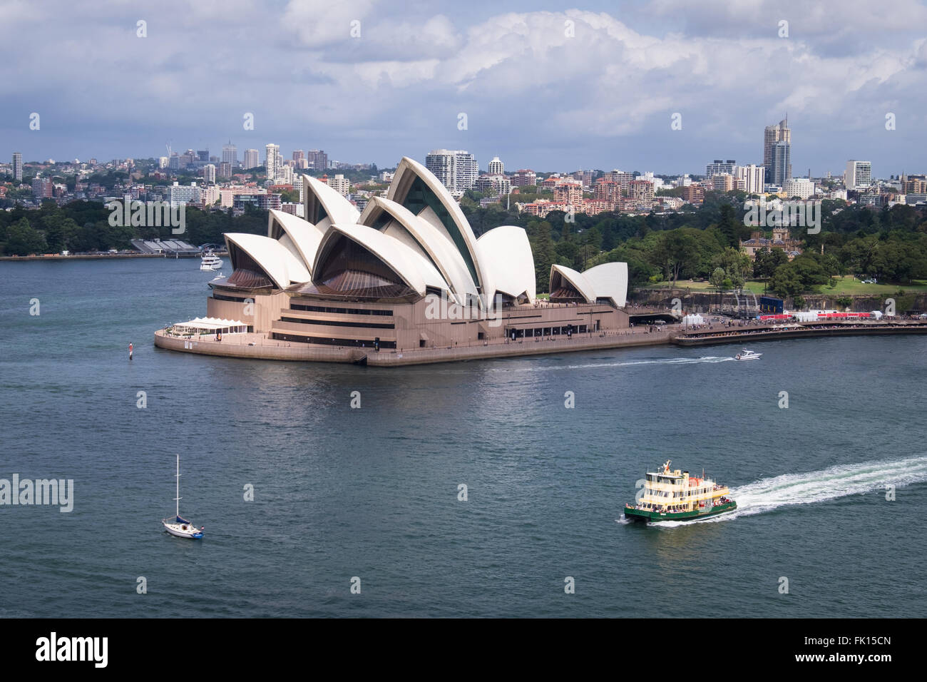 A yacht and ferry sail in Sydney Harbour past the Sydney Opera House Stock Photo