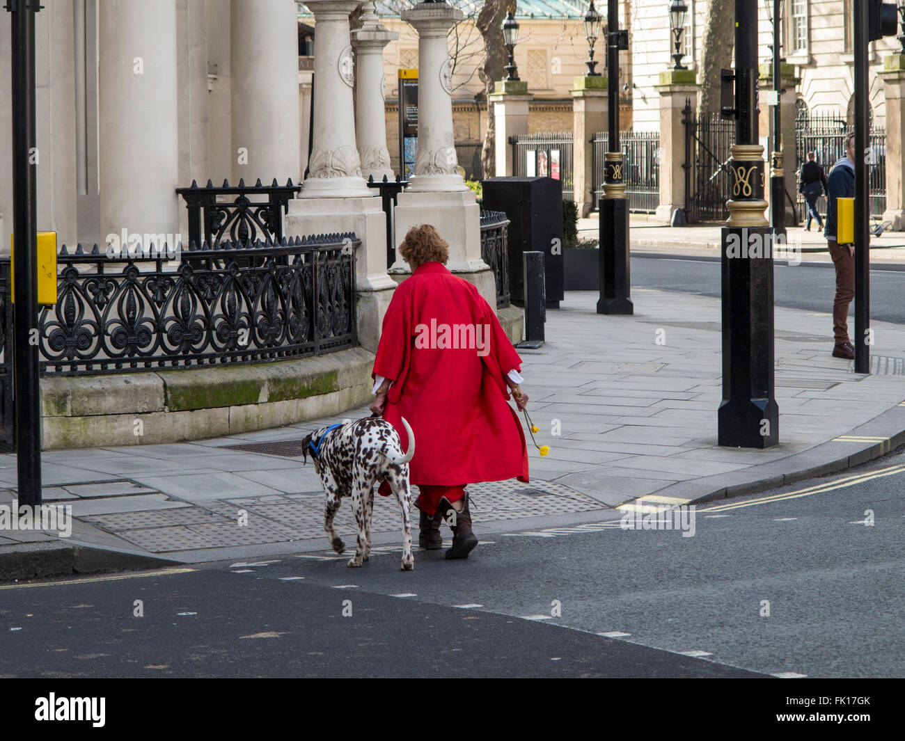 A lady in a red coat with a dalmation dog in central london Stock Photo