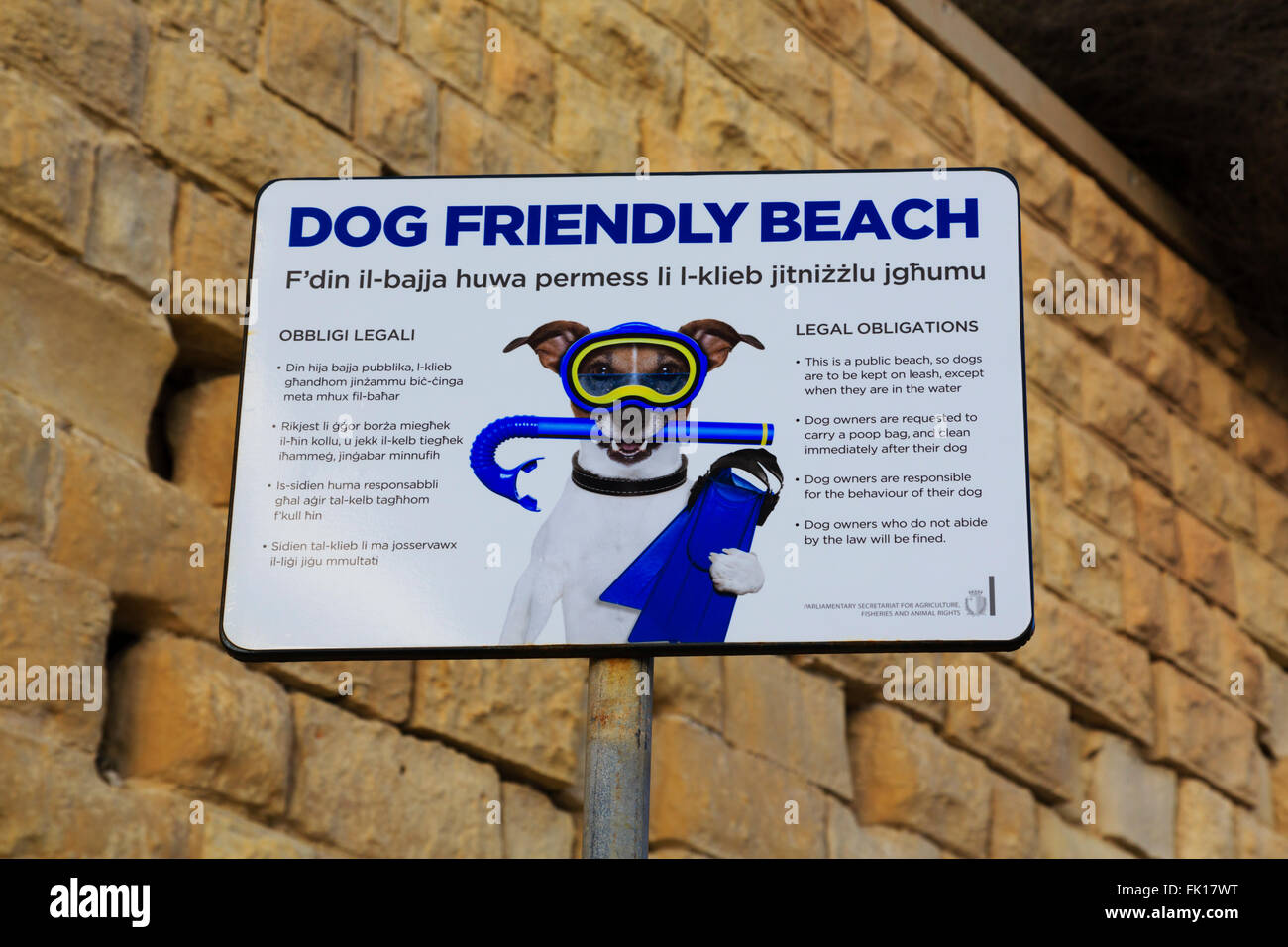 'Dog friendly beach' sign in English and Maltese, giving legal obligations to dog owners. Stock Photo